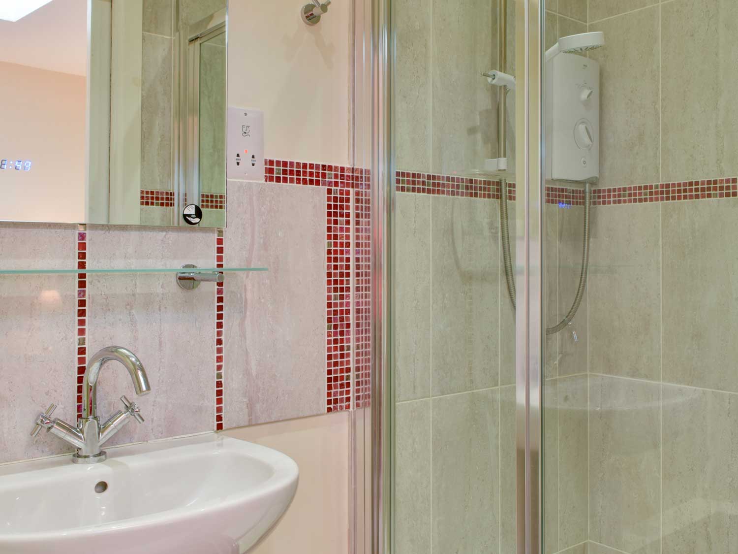 Bathroom featuring white porcelain sink, shower cubicle and mirror with digital time display